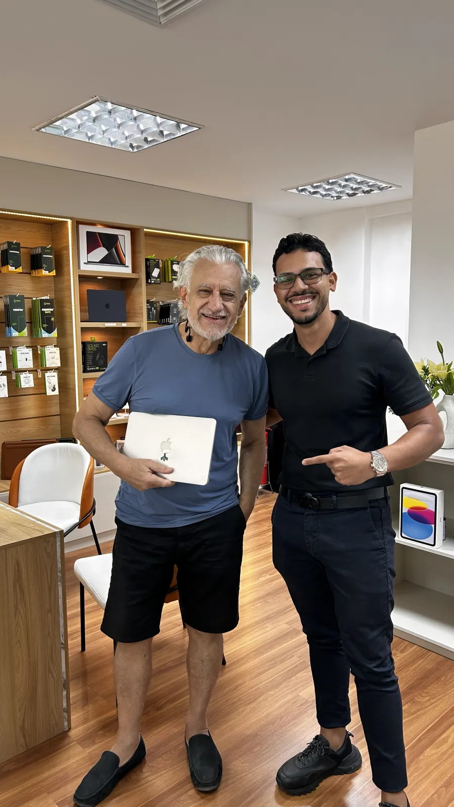 Cliente da iPlus recebendo o MacBook reparado, com garantia